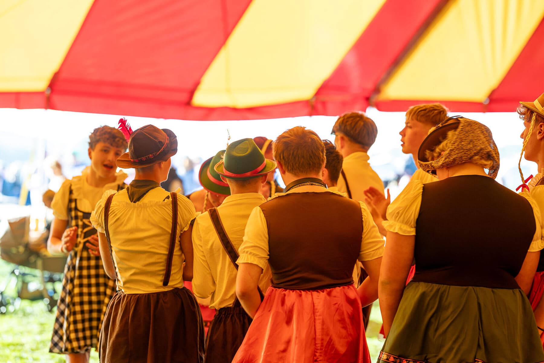 Young players in fancy dress under a striped festival marquee